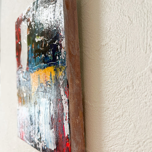 斜めから見た「動的調和02」。色と形が融合し、動きのある抽象的な表現が豊かなテクスチャーと共に立体感を持って現れる。227×158mmのサイズ。A diagonal perspective of “Dynamic Harmony 02.” The fusion of colors and forms, combined with dynamic abstract expression, creates a textured depth in the piece. Size: 227×158mm.