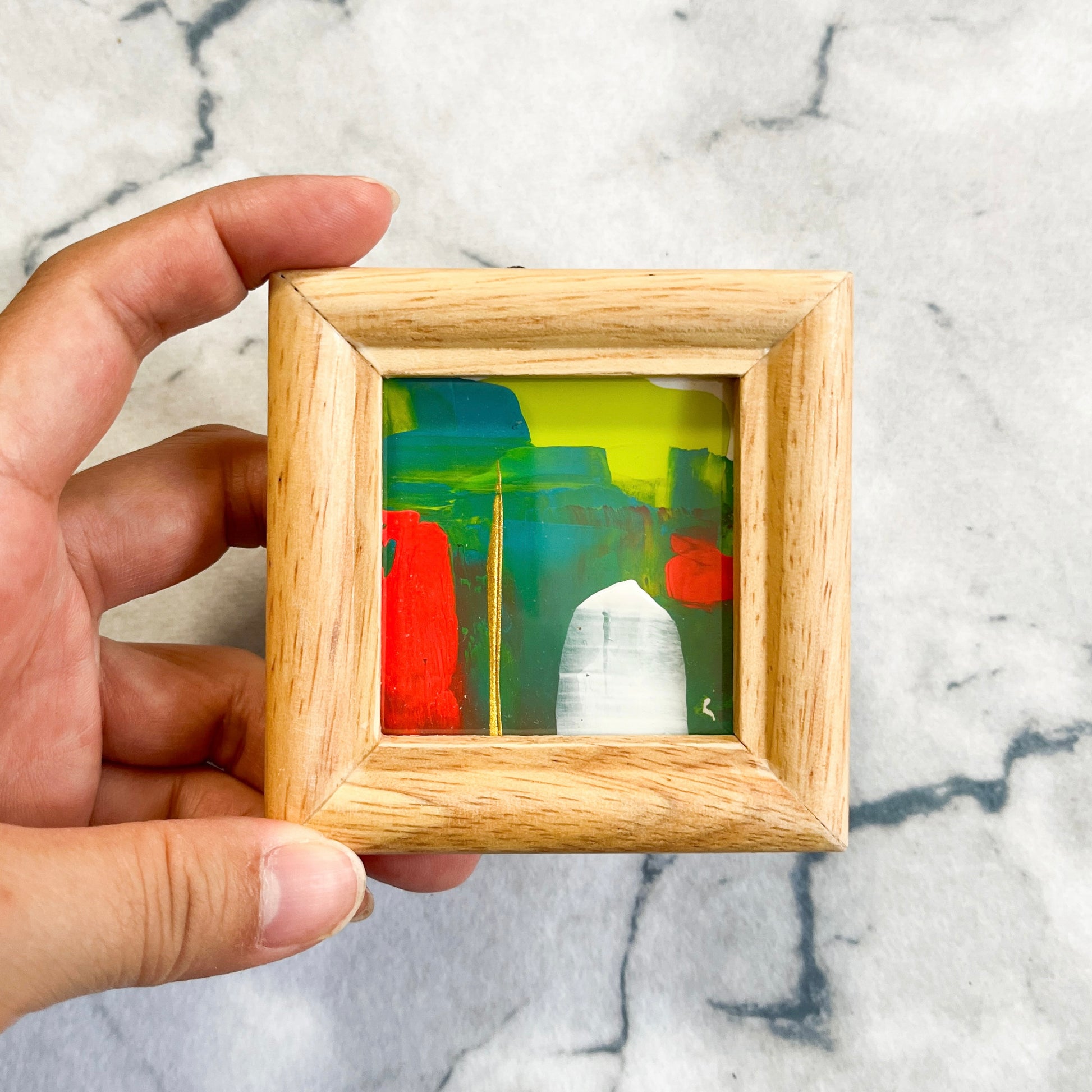 Yuka Mitsufujiの小さなフレーム付き抽象画を手で持った様子 / A small framed abstract painting by Yuka Mitsufuji held in hand, palm-sized original artwork Light Green and Red