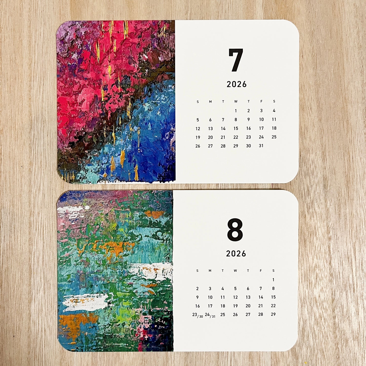 Yuka Mitsufuji 2026 desk calendar on desk, two months open, featuring colorful abstract artworks / Yuka Mitsufuji 2026年カレンダー、デスク上に並べた2ヶ月分見開き、カラフルな抽象画作品