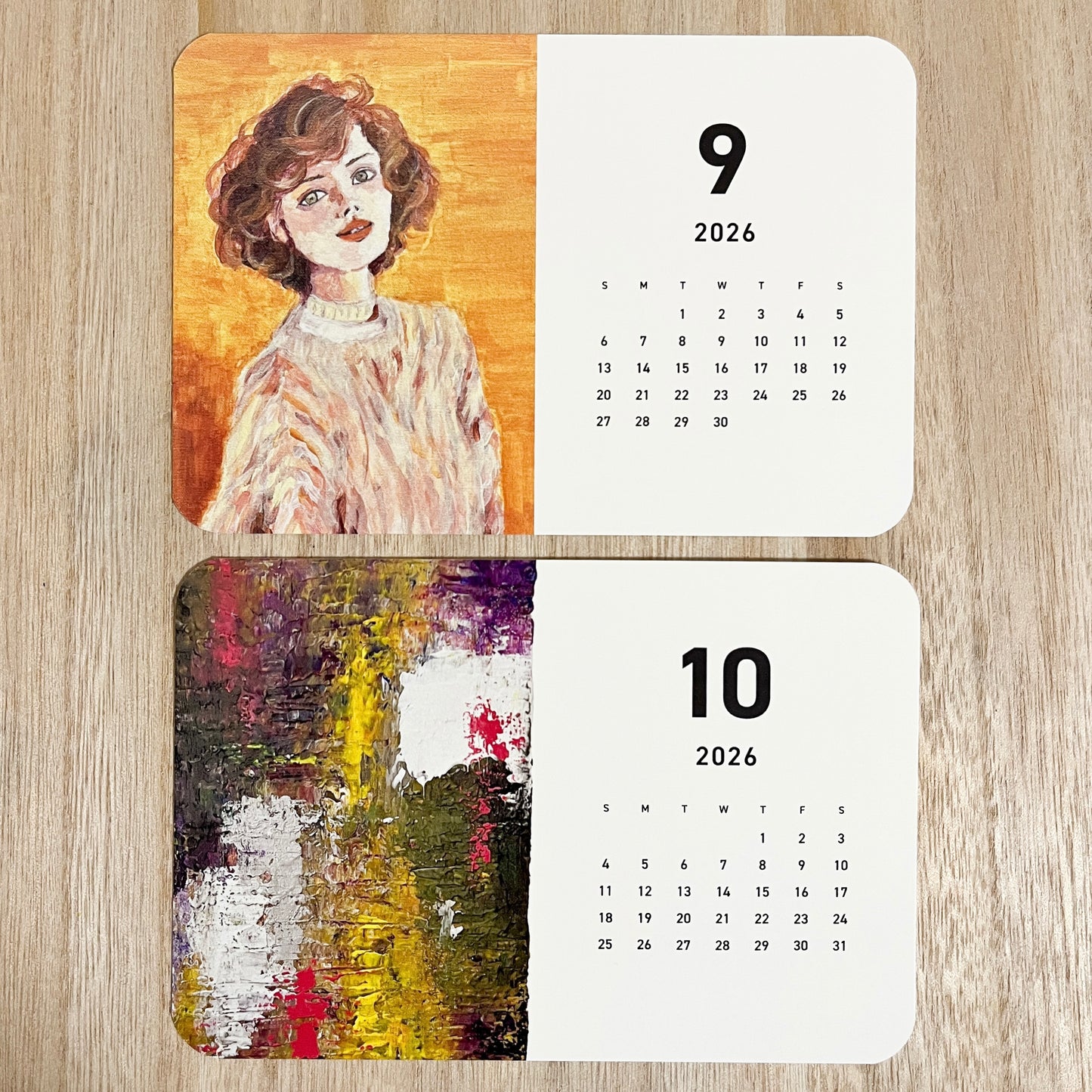 Close-up of Yuka Mitsufuji 2026 calendar showing two months, blending vibrant contemporary art and oil-style acrylic female portraits / Yuka Mitsufuji 2026年カレンダー、2ヶ月分クローズアップ、鮮やかな現代アートとアクリル絵の具で描いた油彩風の女性肖像画